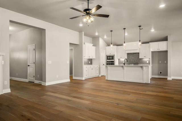 kitchen featuring white cabinets, dark hardwood / wood-style flooring, a kitchen island with sink, and hanging light fixtures