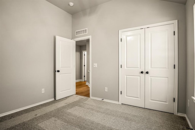 unfurnished bedroom with light colored carpet and a closet