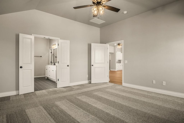 unfurnished bedroom featuring high vaulted ceiling, ceiling fan, dark carpet, and connected bathroom