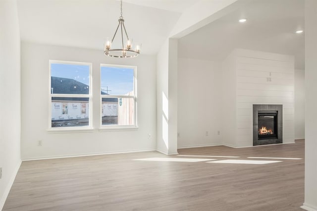 unfurnished living room with light hardwood / wood-style floors, vaulted ceiling, and an inviting chandelier