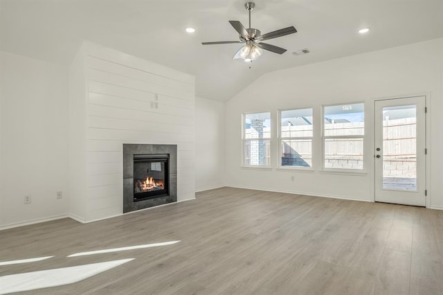 unfurnished living room featuring a tile fireplace, light wood-type flooring, ceiling fan, and lofted ceiling