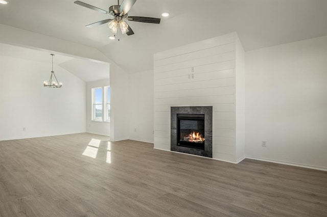 unfurnished living room featuring a tile fireplace, hardwood / wood-style flooring, and vaulted ceiling