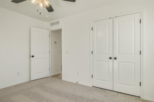 unfurnished bedroom featuring ceiling fan, light colored carpet, and a closet