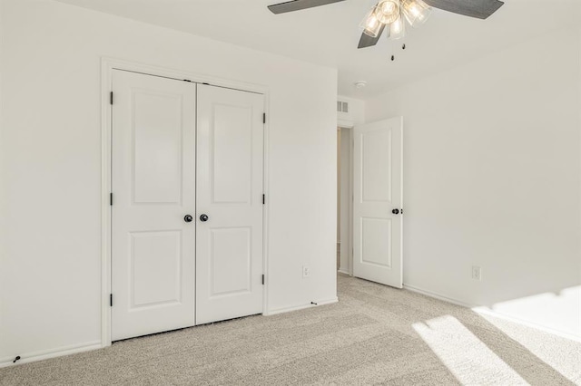 unfurnished bedroom featuring ceiling fan, a closet, and light colored carpet