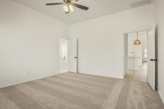 spare room featuring ceiling fan, light colored carpet, and a high ceiling