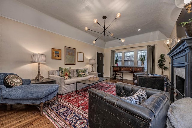 living room with a chandelier, wood finished floors, a tile fireplace, and vaulted ceiling