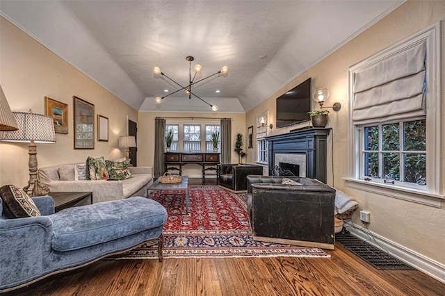 living area with wood finished floors, lofted ceiling, a fireplace, an inviting chandelier, and a textured wall