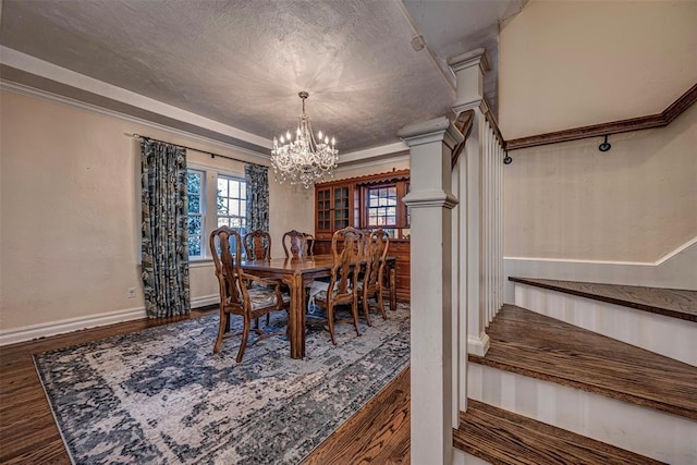 dining space with wood finished floors, baseboards, a textured ceiling, crown molding, and a notable chandelier