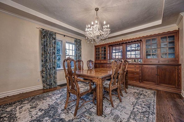 dining space featuring crown molding, wood finished floors, a tray ceiling, a textured wall, and a textured ceiling