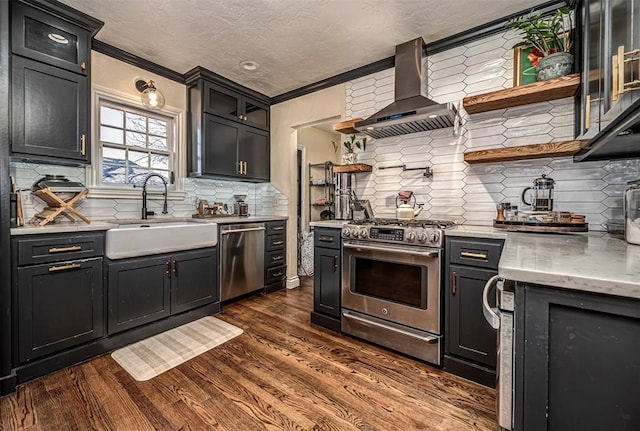 kitchen with a sink, dark wood finished floors, stainless steel appliances, wall chimney exhaust hood, and open shelves