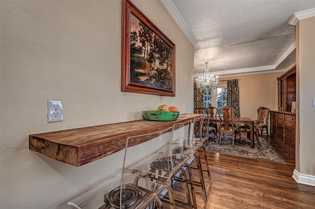 dining space featuring crown molding, wood finished floors, a textured wall, and a chandelier