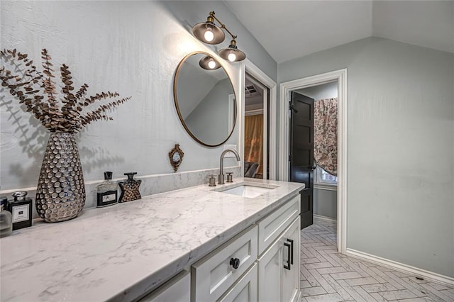 bathroom with baseboards, vanity, and vaulted ceiling