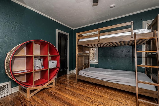 bedroom featuring visible vents, a textured wall, and wood finished floors