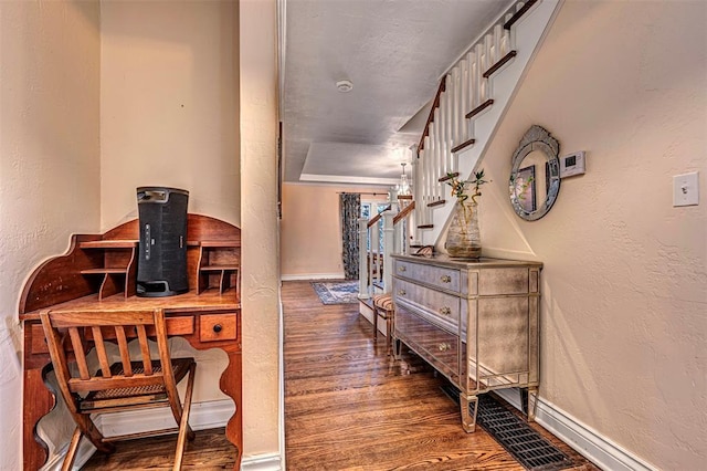 interior space featuring baseboards, a textured wall, and wood finished floors