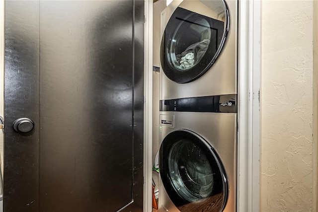 washroom featuring laundry area, stacked washer and clothes dryer, and a textured wall