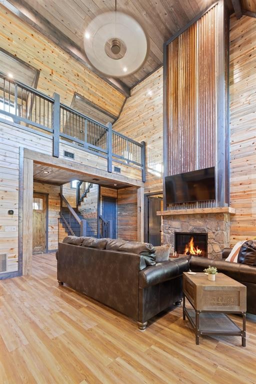 living room featuring wood walls, high vaulted ceiling, and light hardwood / wood-style flooring