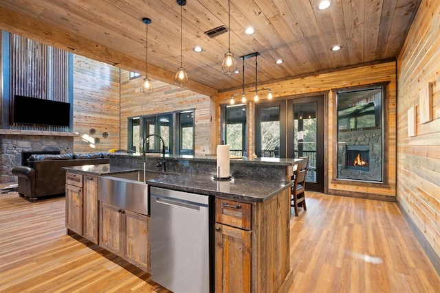 kitchen featuring dishwasher, dark stone countertops, wood walls, a spacious island, and decorative light fixtures