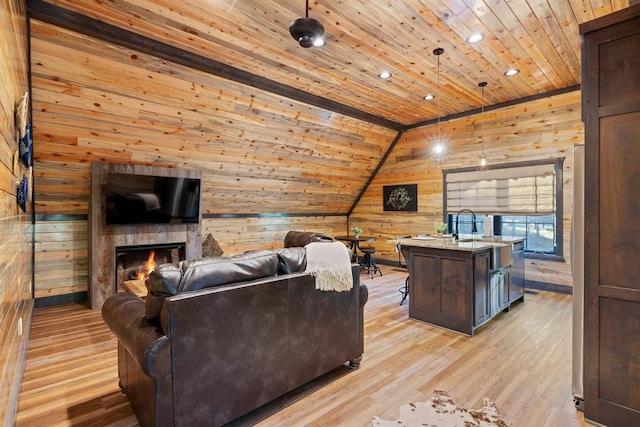 living room featuring wood walls, wooden ceiling, sink, vaulted ceiling, and light hardwood / wood-style flooring