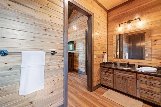 bathroom with wood-type flooring, vanity, and wood walls