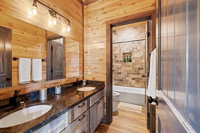 full bathroom with wood walls, wood-type flooring, toilet, shower / bath combo with shower curtain, and vanity