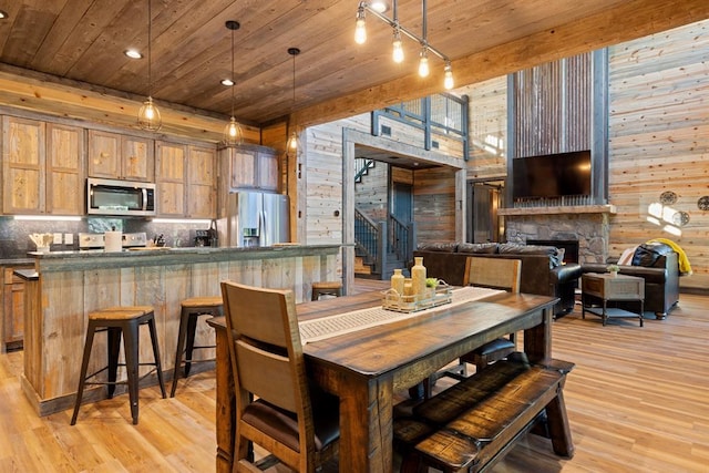 dining area with wood walls, a fireplace, a wealth of natural light, light hardwood / wood-style floors, and wood ceiling