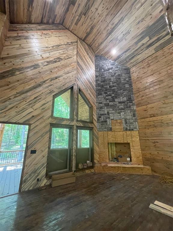 unfurnished living room featuring wooden walls, high vaulted ceiling, wooden ceiling, and a wealth of natural light