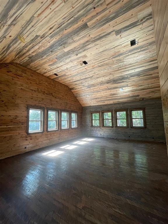 empty room featuring lofted ceiling, wood walls, and wood ceiling