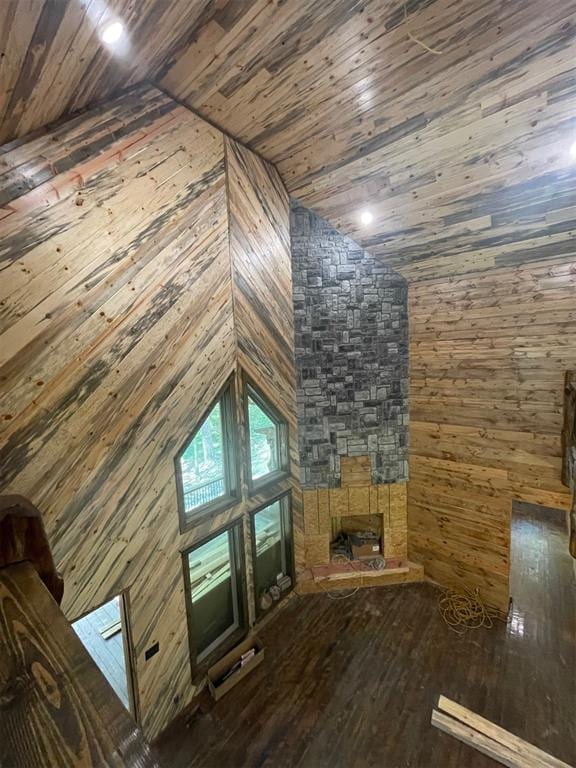 unfurnished living room with lofted ceiling, wood-type flooring, wooden walls, and wooden ceiling