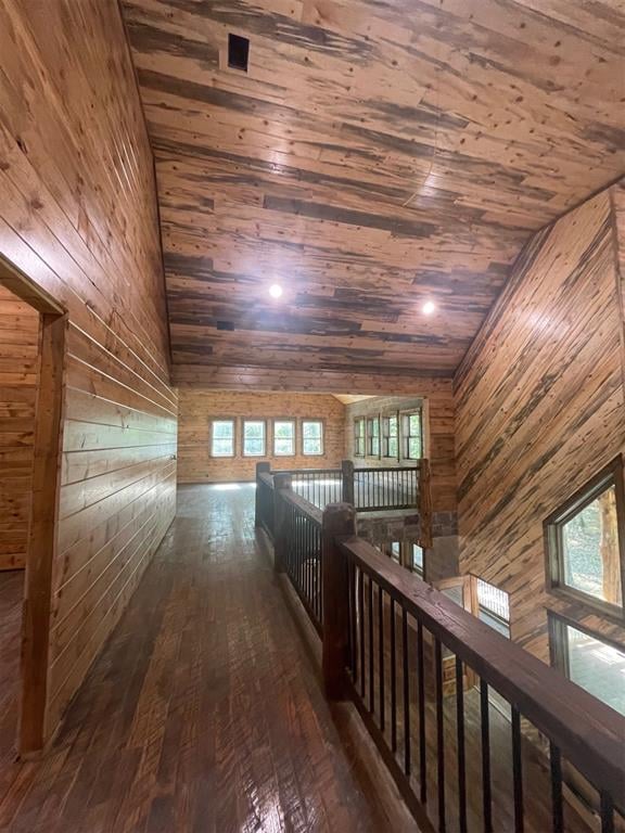 hallway featuring dark hardwood / wood-style floors, wood walls, wooden ceiling, and vaulted ceiling