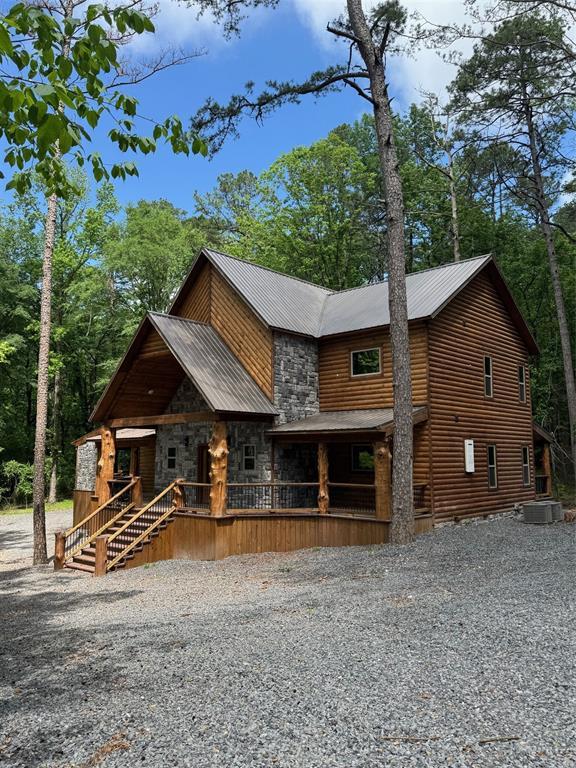 chalet / cabin with covered porch, driveway, and metal roof