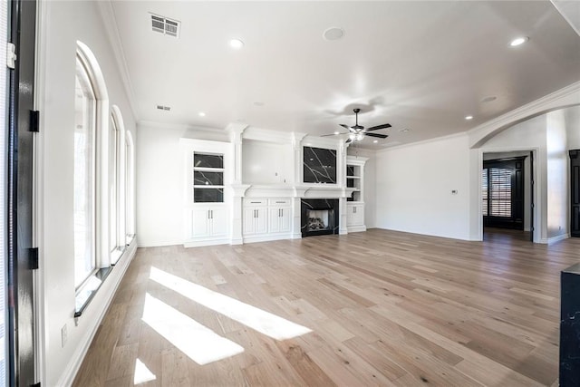 unfurnished living room with ceiling fan, crown molding, a high end fireplace, and light hardwood / wood-style flooring