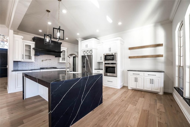 kitchen with a spacious island, pendant lighting, stainless steel appliances, and light hardwood / wood-style floors