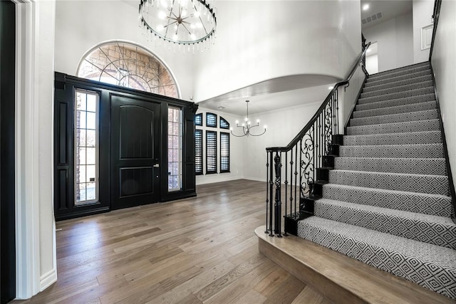 entrance foyer featuring hardwood / wood-style flooring, a towering ceiling, and a chandelier