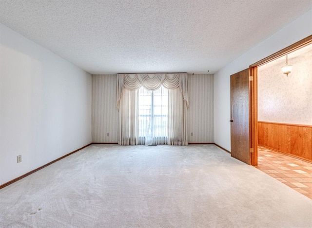 carpeted empty room with wood walls and a textured ceiling