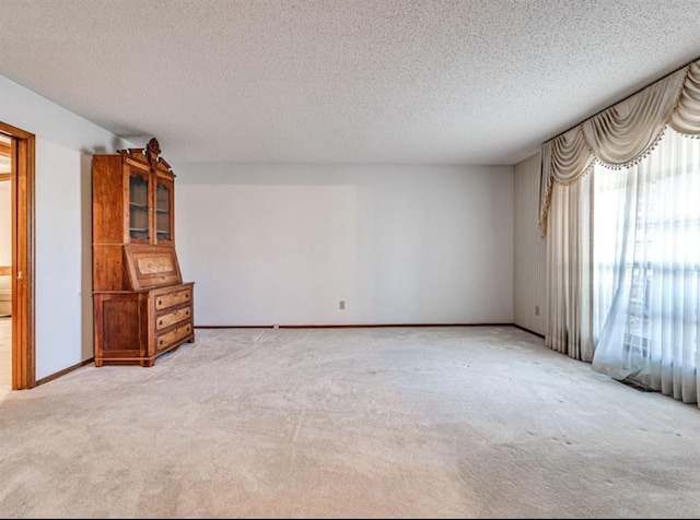 empty room with a textured ceiling and light carpet