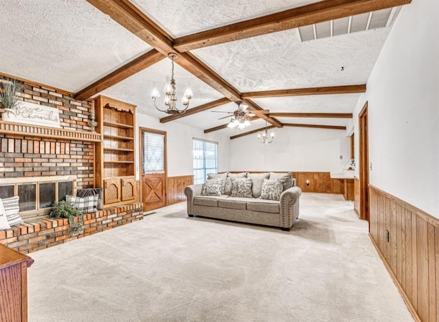 living room with wood walls, lofted ceiling with beams, a brick fireplace, a textured ceiling, and light colored carpet