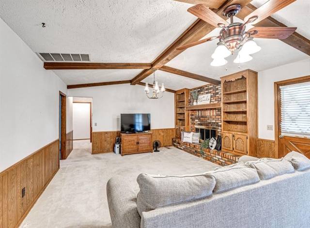 living room featuring built in shelves, a textured ceiling, ceiling fan with notable chandelier, a fireplace, and vaulted ceiling with beams