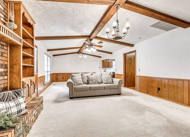 carpeted living room with vaulted ceiling with beams, wood walls, a textured ceiling, and ceiling fan with notable chandelier