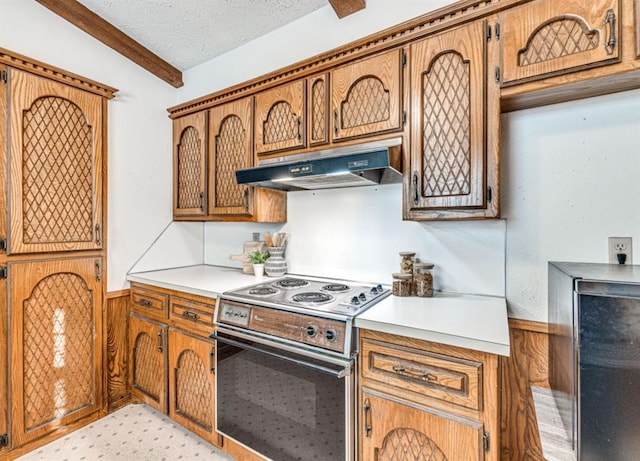 kitchen featuring a textured ceiling, wooden walls, electric range oven, and lofted ceiling