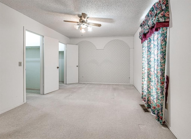 empty room with a textured ceiling, ceiling fan, and light carpet