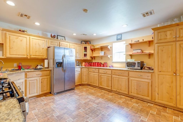 kitchen with light brown cabinetry, stainless steel appliances, light stone counters, and sink