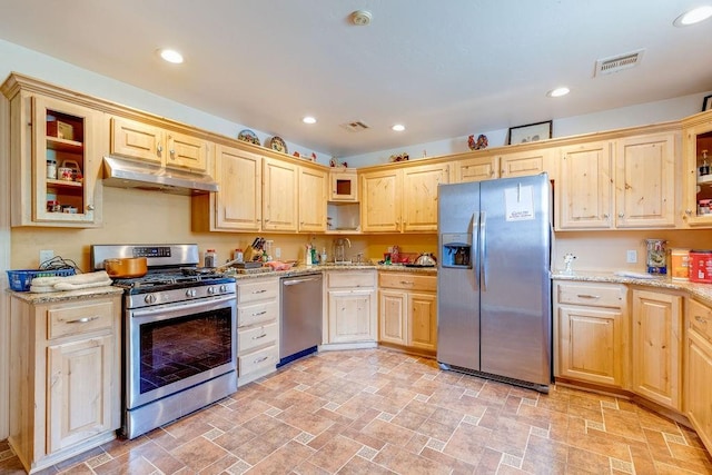 kitchen featuring appliances with stainless steel finishes, light stone counters, light brown cabinetry, and sink