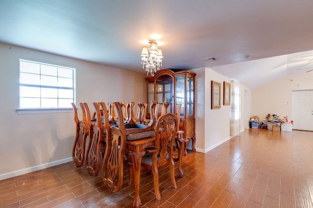 dining space with vaulted ceiling, hardwood / wood-style flooring, and an inviting chandelier