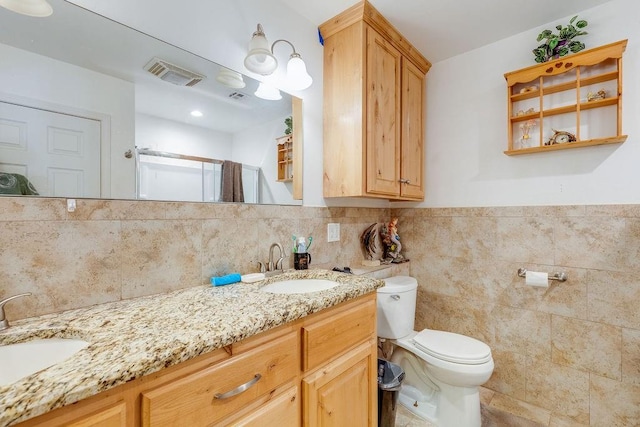 bathroom with vanity, tile walls, and toilet