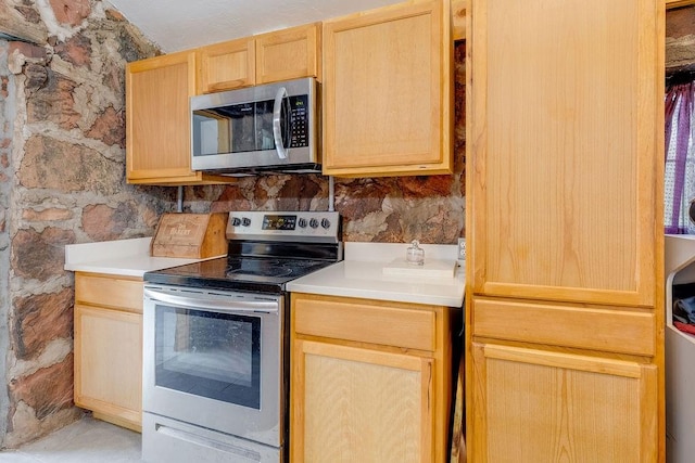 kitchen with decorative backsplash, light brown cabinets, and stainless steel appliances