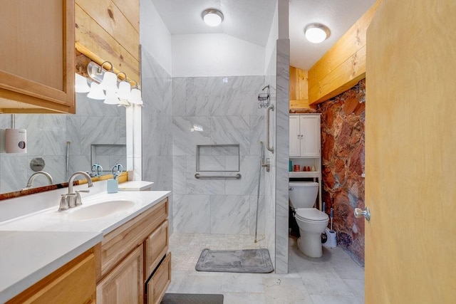 bathroom with a tile shower, vanity, vaulted ceiling, tile patterned flooring, and toilet