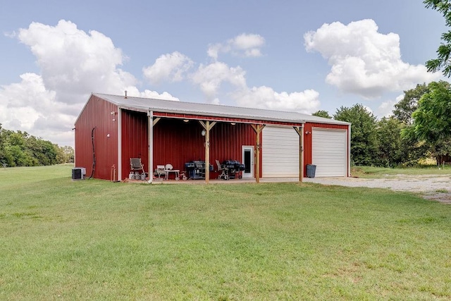 view of outdoor structure featuring a lawn, a garage, and central AC