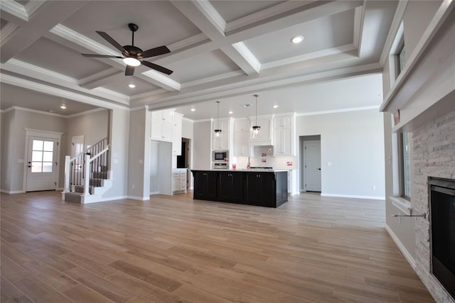 unfurnished living room with ceiling fan, coffered ceiling, light hardwood / wood-style flooring, crown molding, and a fireplace