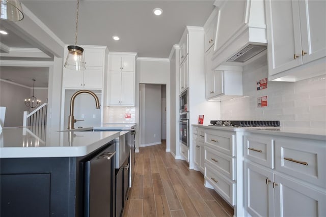 kitchen with appliances with stainless steel finishes, decorative light fixtures, white cabinets, custom range hood, and ornamental molding