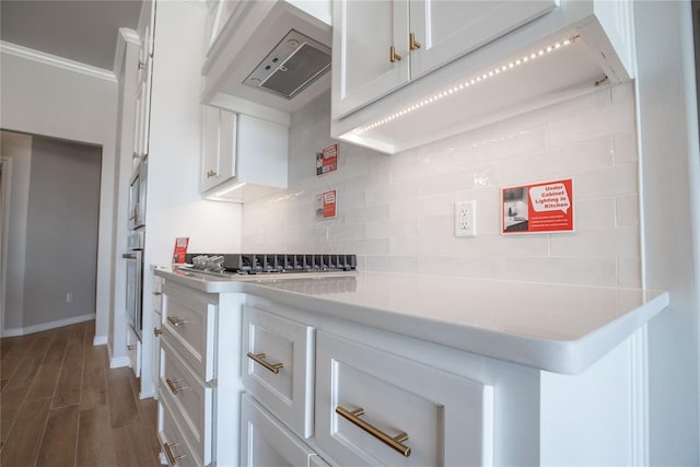 kitchen with dark wood-type flooring, premium range hood, backsplash, white cabinets, and appliances with stainless steel finishes